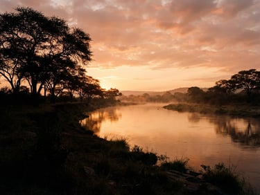 Wide-angle panoramic view of the Kafue River at sunrise, mist rising from the calm water, silhouettes of acacia trees against a dusty ochre sky, low-angle natural light, 35mm film style.