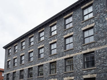 Architectural photography of a classic brick apartment building with newly restored masonry, crisp overcast daylight, cool slate tones, sharp focus.