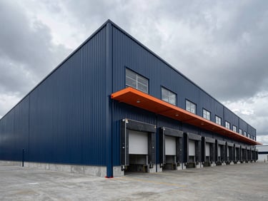 Low-angle architectural shot of a newly completed modern logistics park with clean steel panels, concrete loading docks, dramatic overcast daylight, wide-angle lens