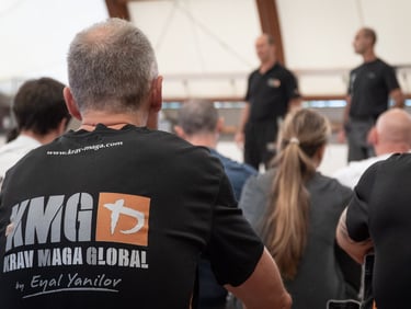 Students in Krav Maga Global t-shirts attend a self-defense seminar led by expert instructors.