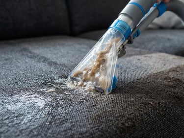 High-detail close-up of a professional extraction nozzle pulling water and dirt from dark grey upholstery, high-key daylight highlighting clean fibers, 35mm.