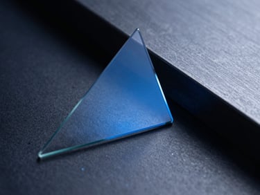 Prism-like abstract reflection of blue light on technical glass and dark steel surfaces.