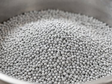Close-up of masterbatch pellets being mixed with raw polymer resin in an industrial blender, bright neutral studio lighting, macro depth of field