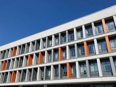 Wide environmental shot of a modern university campus building facade on a clear day, sharp details, deep blue sky.