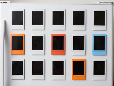 Collection of 3D printed magnetic Instax photo frames on a refrigerator, featuring various shapes and colors, clean studio lighting.