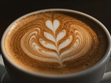 Close-up of latte art in a ceramic cup, warm golden hour light, shallow depth of field, moody editorial photography.
