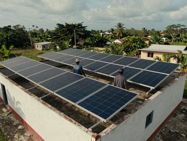 Environmental wide shot of a solar panel installation on a low rooftop in a rural Cuban setting, overcast sky, two workers visible from behind adjusting panel mounts, no eye contact, natural documentary light