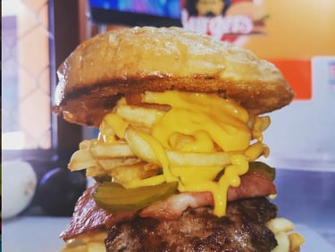 Hamburguesa gourmet de ternera cubierta con patatas fritas crujientes, salsa de queso cheddar.