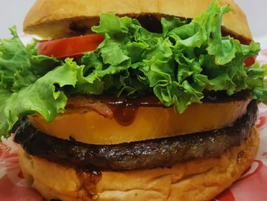 Jugosa hamburguesa de ternera a la parrilla con lechuga fresca, tomate, piña y salsa barbacoa en un pan tostado.