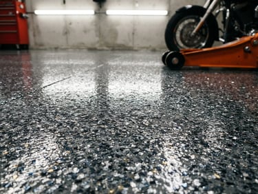 Low-angle close-up of a perfectly coated titanium gray garage floor with metallic chips reflecting overhead utility lights, crisp 35mm industrial photography