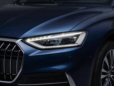 Close-up of a modern dark blue executive sedan's front grille and LED headlight, crisp reflections, dramatic low-key studio lighting