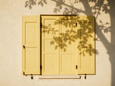 Close-up of elegant yellow shutters on a warm cream cottage wall, sun-dappled shadows from nearby leaves, warm editorial 35mm film style