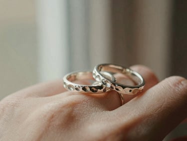 Close-up of hand-hammered silver rings catching soft afternoon window light, shallow depth of field, warm New England tones, 35mm