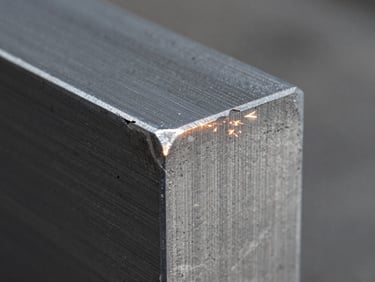 Macro close-up of a clean laser-cut edge on a thick steel plate, cool metallic tones, sharp details