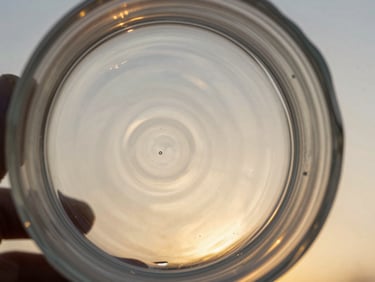 Extreme close-up of hand-poured glass with subtle organic ripples, low-angle golden hour light refracting through the material.