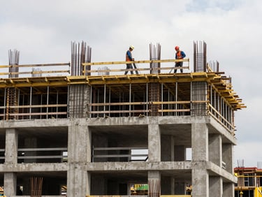 Active construction site mid-pour, workers in hard hats pouring concrete on a multi-story building frame, natural overcast daylight, scaffolding and rebar in the foreground