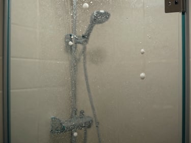 Close-up shot of a bathroom glass shower door with heavy soap scum buildup and water mineral spots.