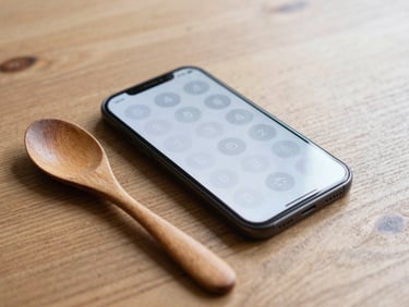 An Android phone showing a grid of circular habit toggles, lying next to a hand-carved wooden spoon on an oak desk, 35mm