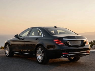 Rear three-quarter view of a black Mercedes-Benz S-Class sedan, soft golden hour reflections, luxurious leather interior visible through glass.