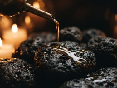Macro photography of warm oil trickling onto basalt stones, low-key amber lighting, soft candlelight glow, shallow depth of field, 35mm