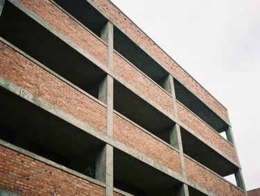 Low angle shot of a brutalist brick building facade in Bogotá, geometric concrete beams, overcast sky, architectural shadow play, 35mm film style