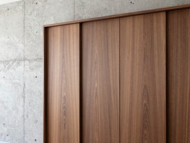 Close-up of a custom-built walnut wardrobe integrated seamlessly into a polished concrete wall, clean lines, minimalist luxury.