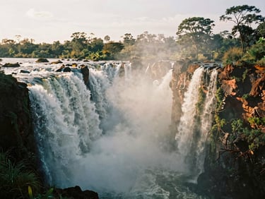 A dramatic landscape of Murchison Falls with mist rising from the churning water, golden-hour light hitting the spray