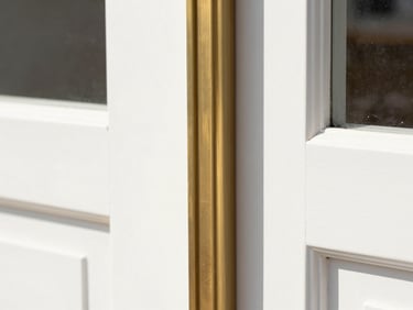 Macro detail of a crisp miter joint on a warm brass-accented door frame, bright daylight, 35mm lens