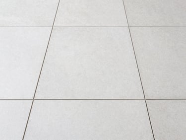 Straight-on symmetrical shot of newly laid light grey ceramic floor tiles with perfectly even grout lines, natural light