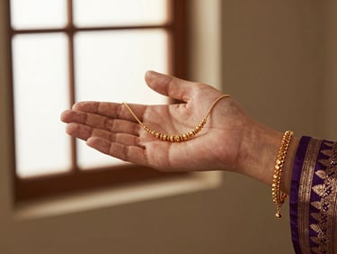 Detail shot of a handmade gold hathphool draped elegantly across a hand, warm directional gallery light.