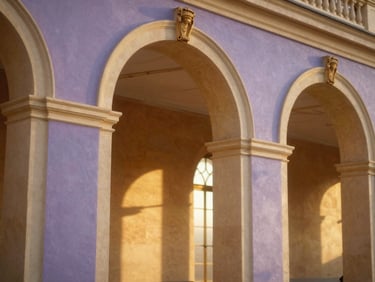 Warm editorial photograph of majestic palace archways, soft golden light, shallow depth of field.
