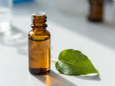 Macro shot of an amber glass apothecary bottle next to a green leaf on a clean, sunlit laboratory counter, soft shadows, clinical-botanical editorial style.