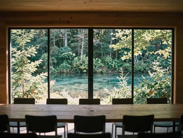 Atmospheric shot of a minimalist meeting space within a cabin, large windows showing forest, natural light, empty chairs, 35mm film