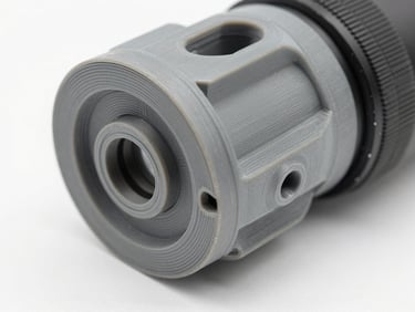Close-up studio photograph of a functional 3D-printed mechanical prototype component in technical grey material on a white surface, studio strobe lighting, sharp detail showing layer precision and material strength, clean white background, no people