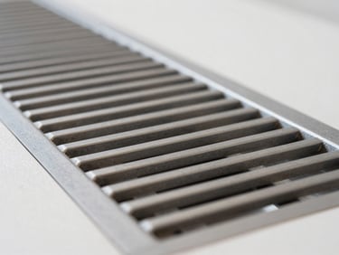 Technical macro shot of a clean metallic ventilation grid, architectural finish, neutral lighting, 35mm lens