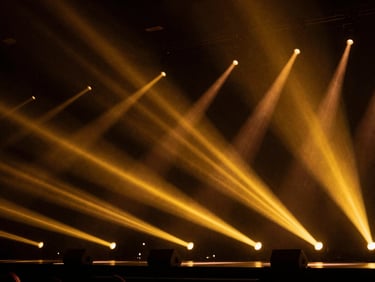 Cinematic luxury photography of a high-end stage setup, dramatic concert lighting with warm golden lasers, rich dark shadows, 35mm