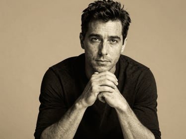 An elegant black and white portrait of a male art director, hands clasped, warm studio lighting, minimal background