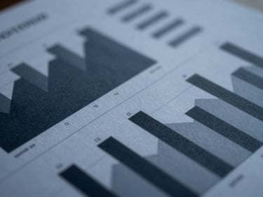 Close-up of a high-quality paper document with financial charts, sharp geometric shadows, cool diffused daylight, deep navy and slate tones, 35mm lens