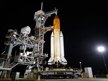 Extreme wide shot of the SLS rocket on the launchpad at night under dramatic floodlights, high-contrast deep shadows, cinematic aerospace photography, 70mm