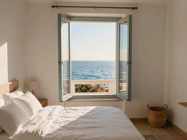 Sunlit cozy pension room with white linens, open window showing the blue sea, warm morning light