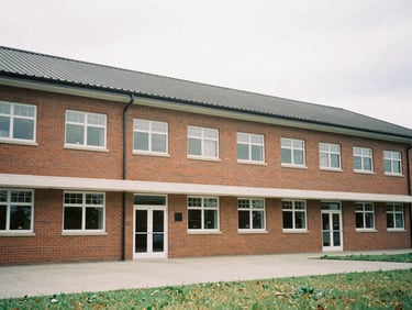 Documentary photograph of a modern brick primary school building with completed roofing, natural overcast light, medium format film, environmental framing.