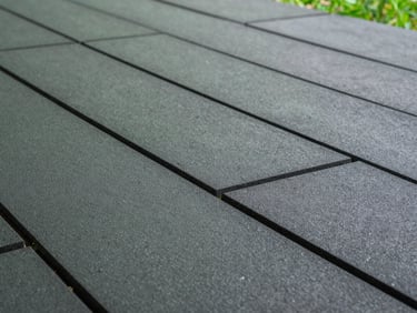 Macro detail shot of interlocking dark gray rubber tiles, perfectly aligned seams, clean architectural lines
