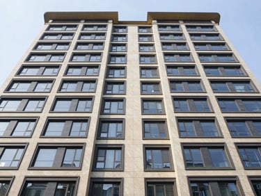 Wide symmetrical architectural shot of a modern luxury apartment facade under crisp morning light, clean lines, high contrast, muted champagne and navy tones, wide-angle lens