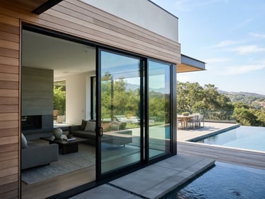 Crisp architectural photography of a minimalist luxury home with large sliding glass doors, bright daylight, clean reflections, sharp focus, 35mm