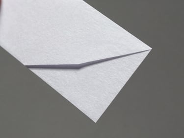 Macro close-up of a physical folded paper prototype, sharp architectural angles, hard directional side-light, crisp shadows on textured paper, 50mm