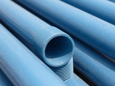 Macro close-up of heavy-duty blue PVC pipes showing thick walls and precise schedule 80 threading, bright daylight, 35mm