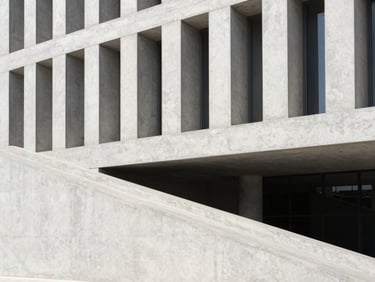 Modern concrete building facade with a clean accessible ramp integrated into the landscape, bright sunlight, sharp geometric lines