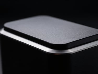 High-contrast studio shot of a minimalist daily utility object, matte black finish with anodized silver accents, dramatic backlighting