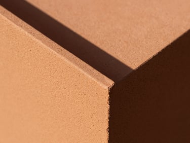 Macro close-up of terracotta-colored textured UV-stable resin surface, sharp geometric shadows, warm direct sunlight, 35mm
