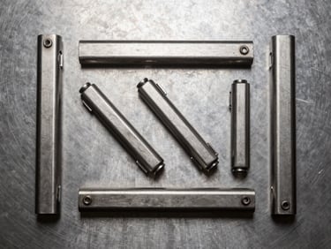 Overhead flat-lay of inoxidable door hardware components laid on a brushed steel surface, task light from above emphasizing surface grain and machined edges, no hands, no text, tight geometric framing